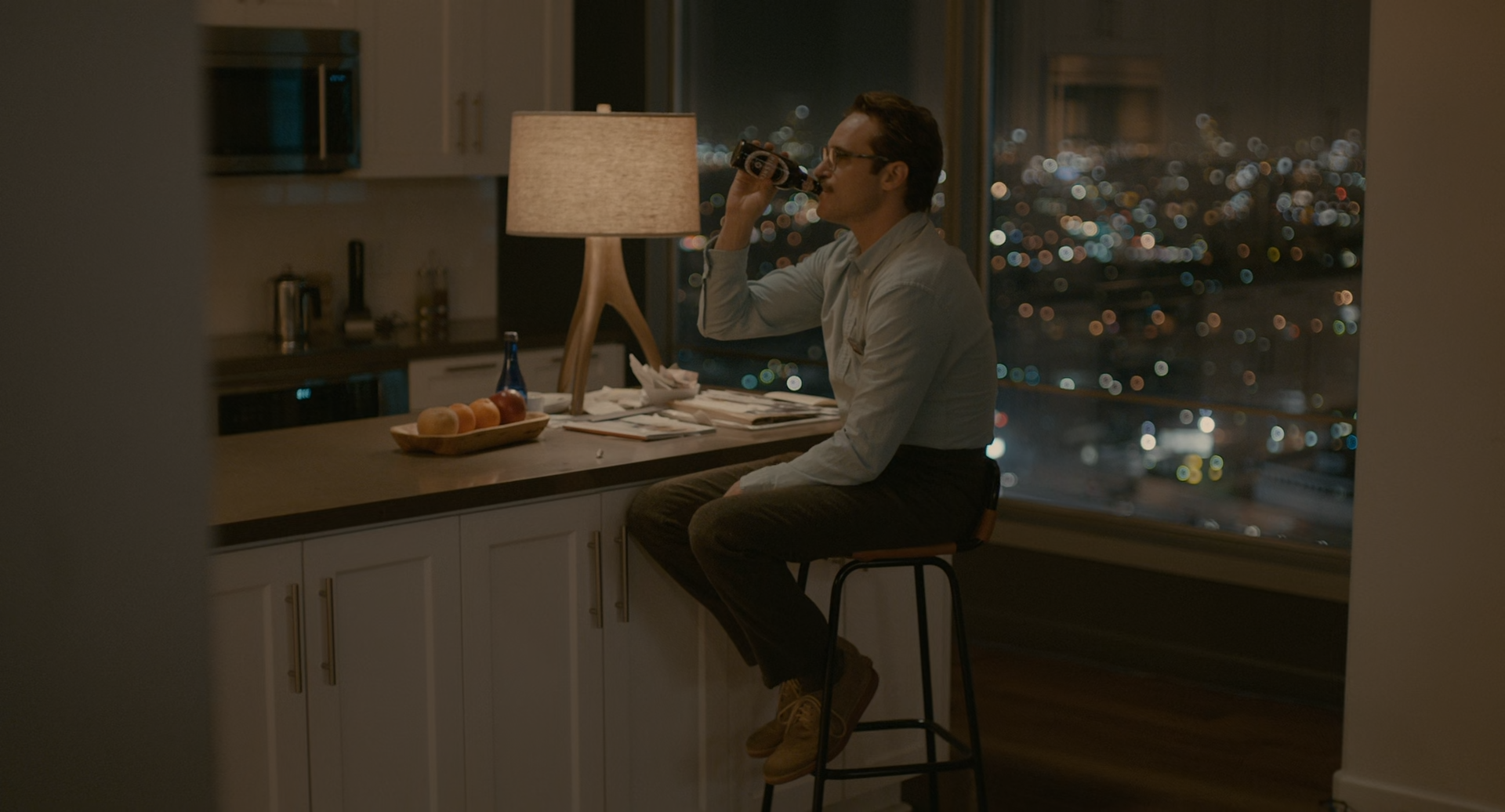 Her screenshot, Theo drinking a bottled beer in his kitchen, wearing the same clothes he wears to work