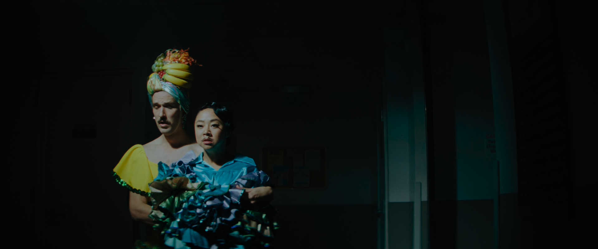 EEAAO Screenshot- The cop wearing a Carmen Miranda drag, Jobu wearing a blue, green, and purple ruffle coat and mustache as the male dance partner