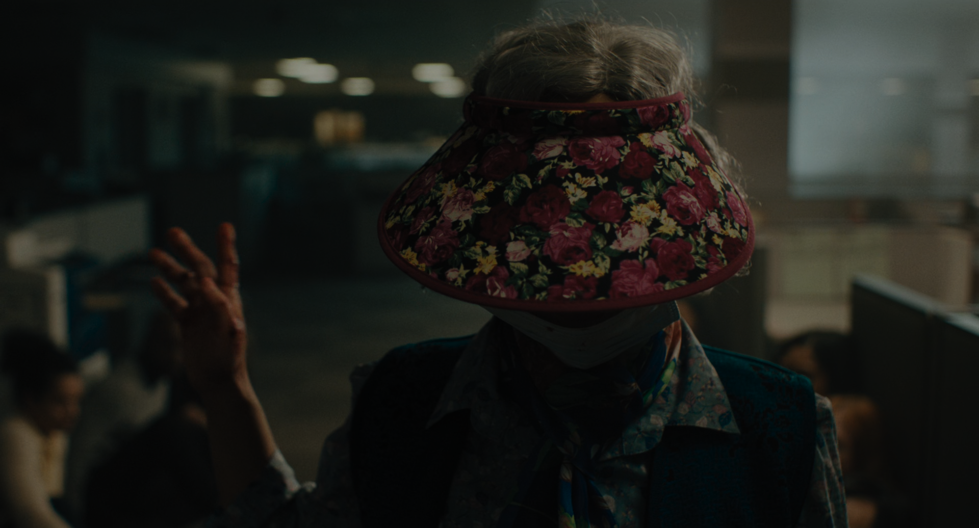 EEAAO Screenshot- Jobu's second look is the aunty-fied version of her first. Wearing a floral visor, surgical mask, and campy floral 70s scarf and lapelled shirt with a blue quilted vest.